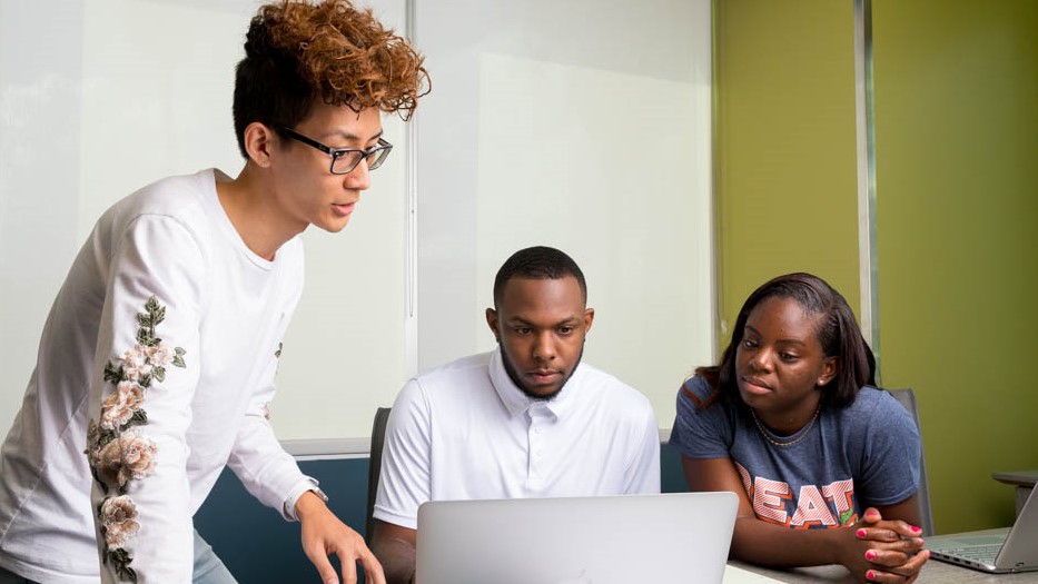 three students sitting at a desk